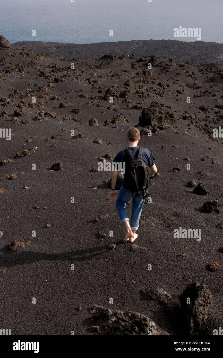 a tourist walks barefoot over volcanic sand at the natural monument Los Volcanes de Teneguía, La Palma, Canary Islands, Spain Stock Photo