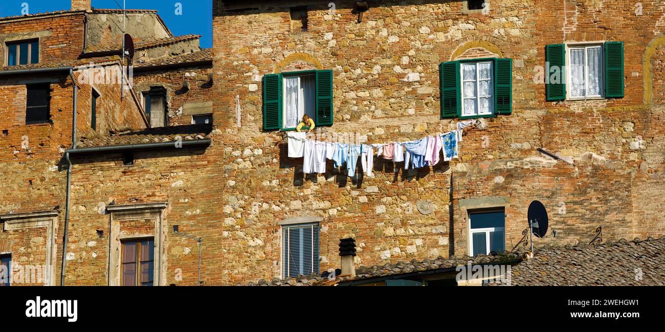 A woman hangs laundry on the façade of a large house in Montepulciano, Tuscany, Italy, Europe Stock Photo