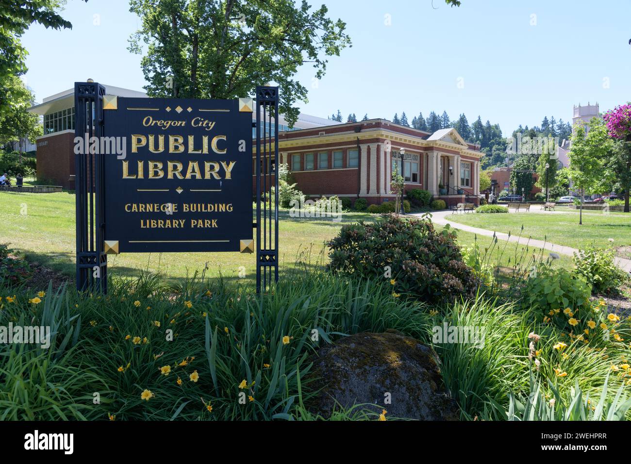 Oregon City, OR, USA - June 11, 2023; Sign for Oregon City Public Library with Carnegie Building in Library Park Stock Photo