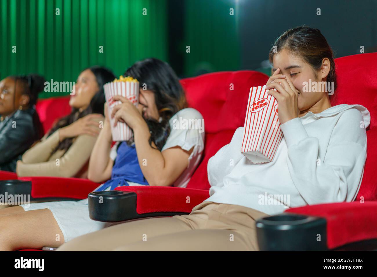 Individuals react to a horror movie on the big screen. This candid moment captures the thrill and fright of the cinematic experience Stock Photo