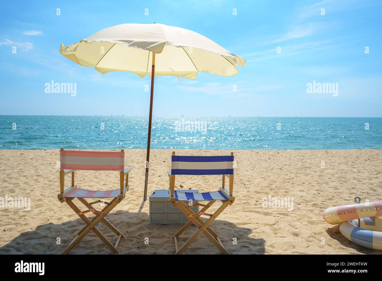 Chair and umbrella perfectly placed on a serene beach invites relaxation, capturing the essence of seaside serenity and the promise of a peaceful esca Stock Photo