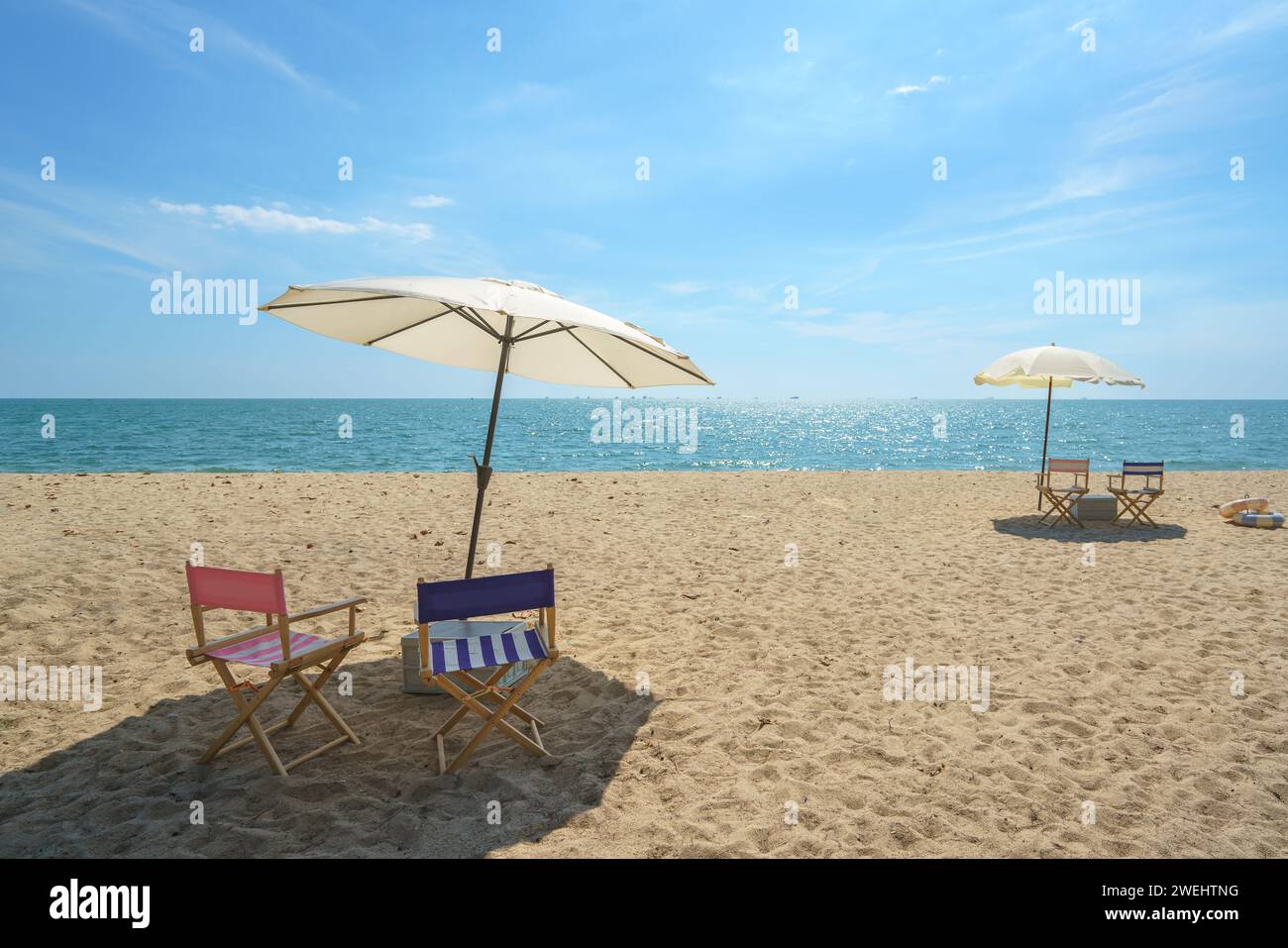 Chair and umbrella perfectly placed on a serene beach invites relaxation, capturing the essence of seaside serenity and the promise of a peaceful esca Stock Photo