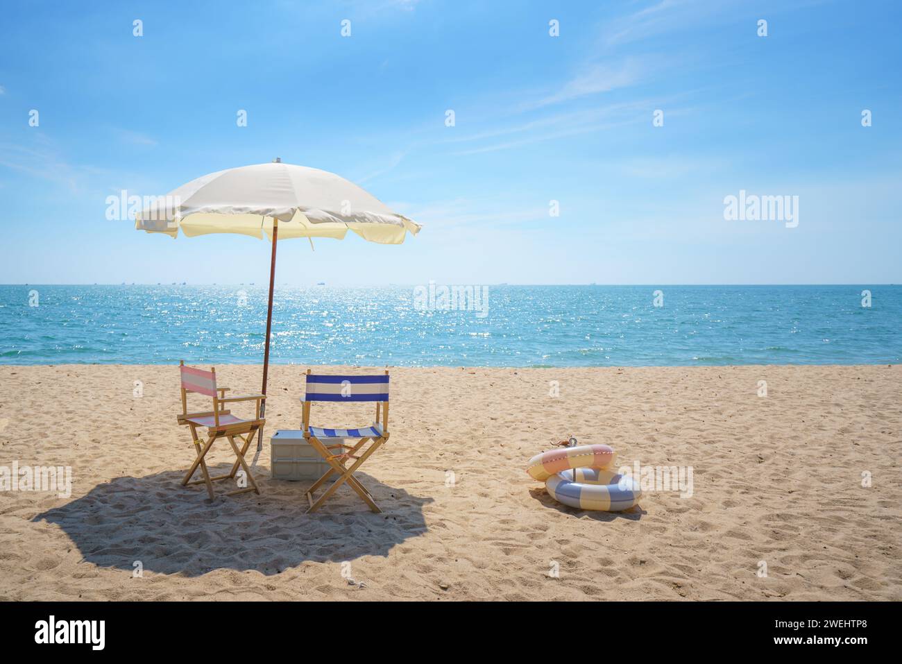 Chair and umbrella perfectly placed on a serene beach invites relaxation, capturing the essence of seaside serenity and the promise of a peaceful esca Stock Photo