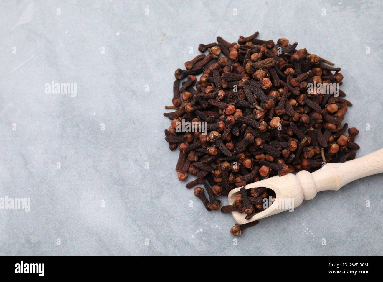 Pile of aromatic dried clove buds and scoop on grey table, top view ...