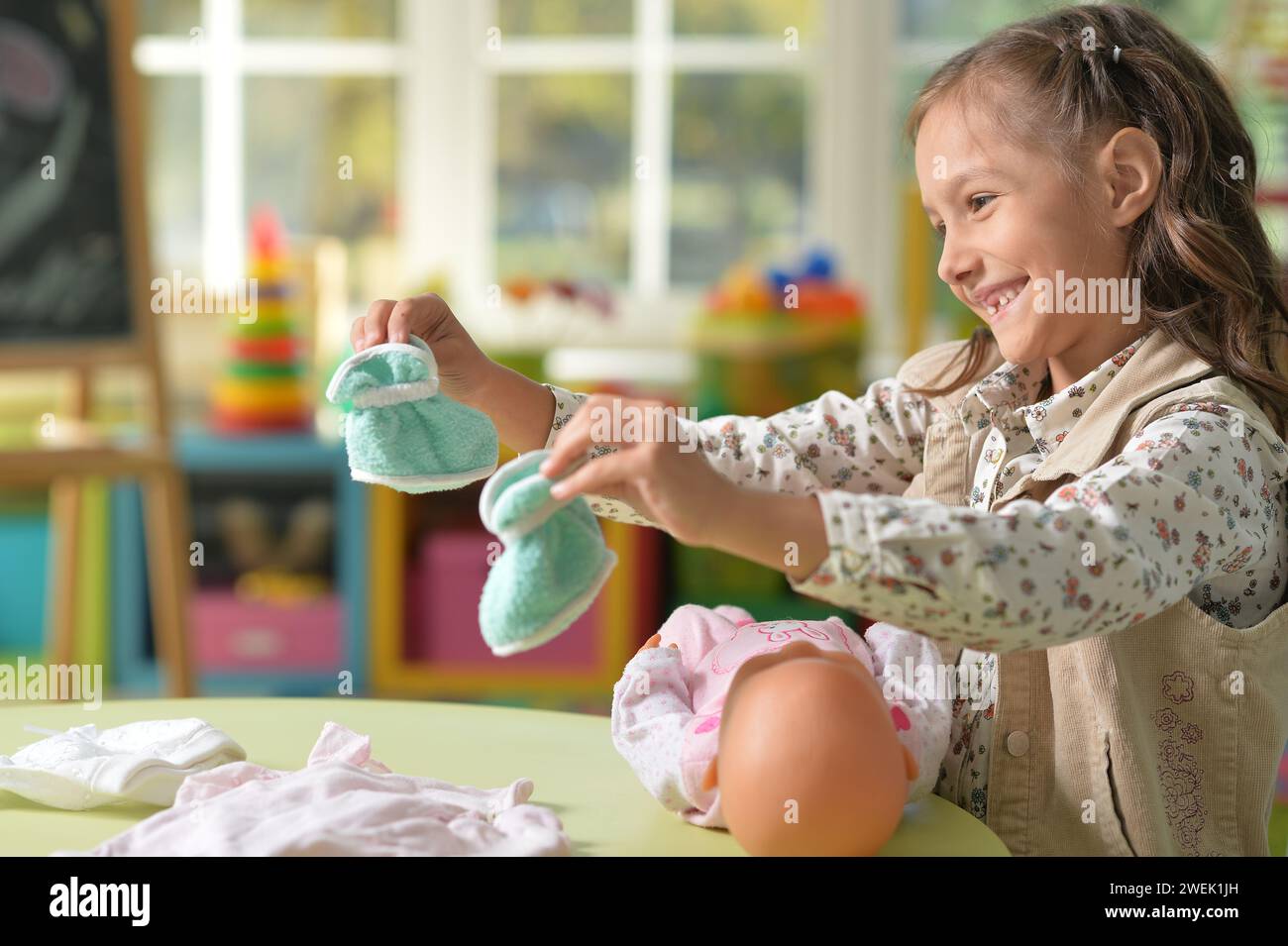 Portrait of cute little girl playing with doll Stock Photo - Alamy