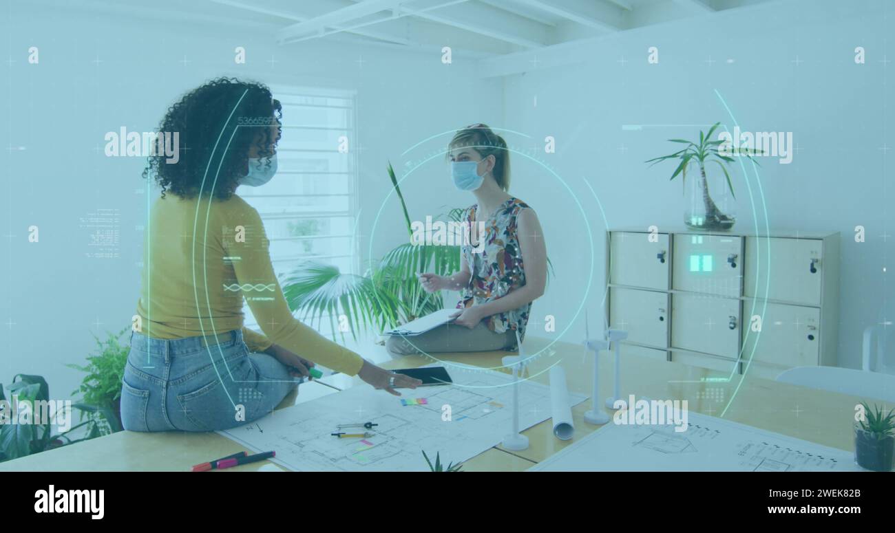 Young biracial woman and young Caucasian woman collaborate in a high-tech office Stock Photo