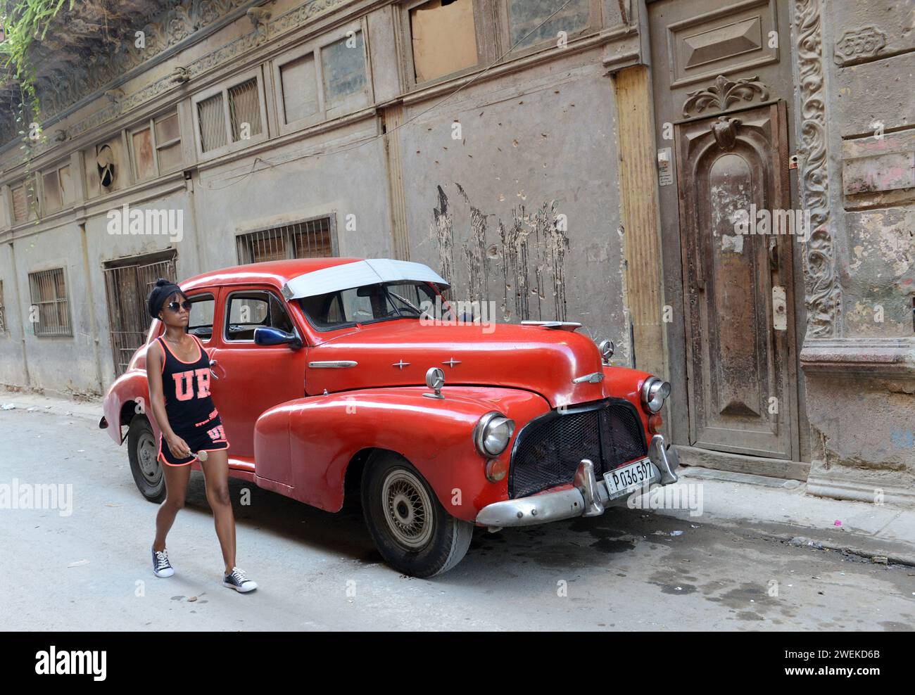 A Cuban woman walking by a vintage Chevrolet car in old Havana, Cuba. Stock Photo