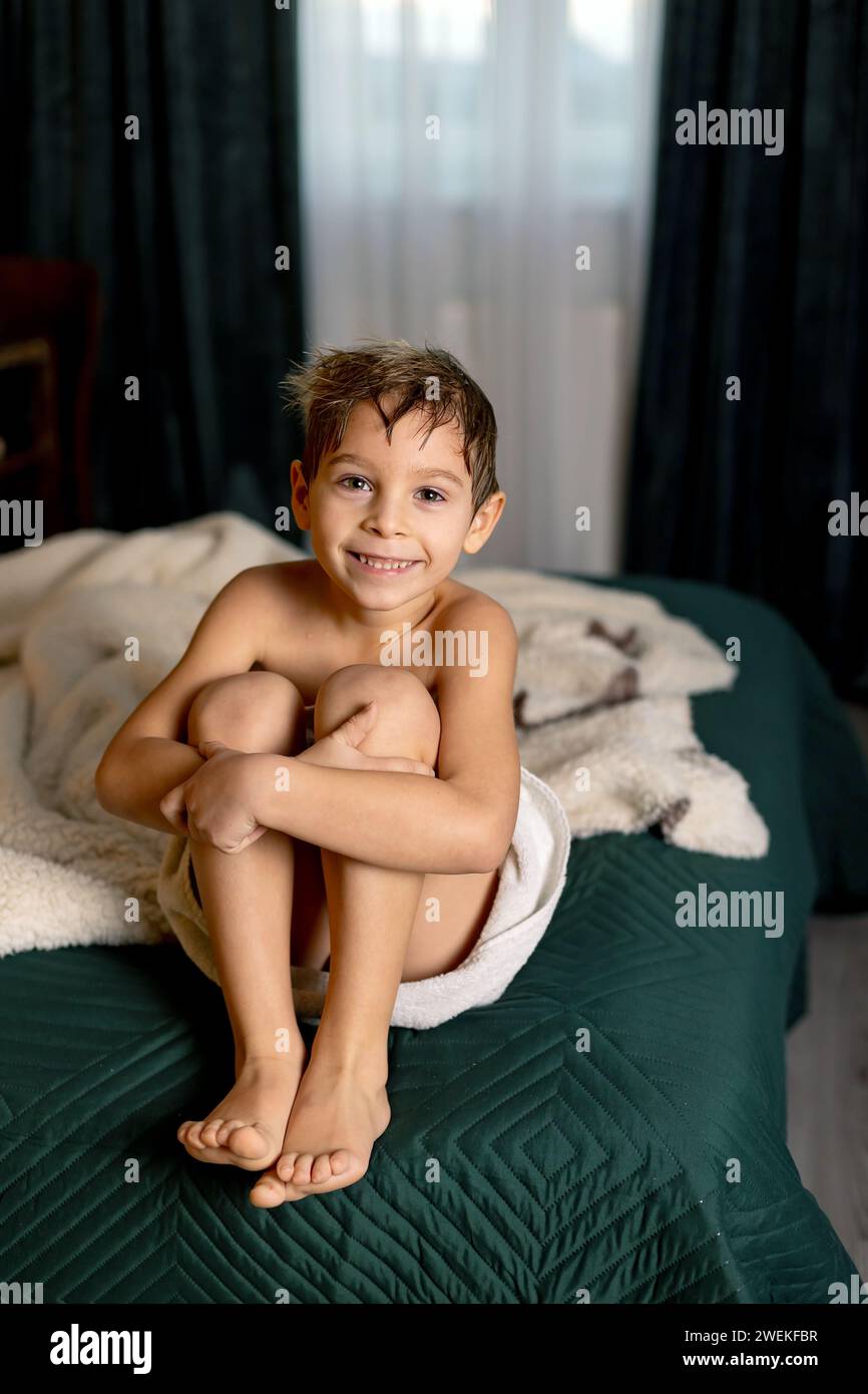 Cute child, boy, sitting at home in bed after shower in towel Stock Photo
