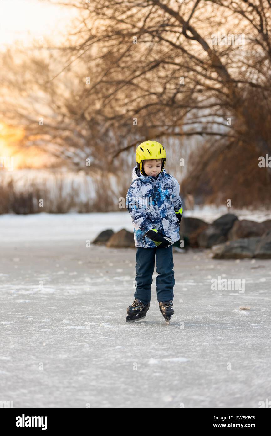 Happy child, boy, skating during the day on frozen lake, having fun outdoors Stock Photo