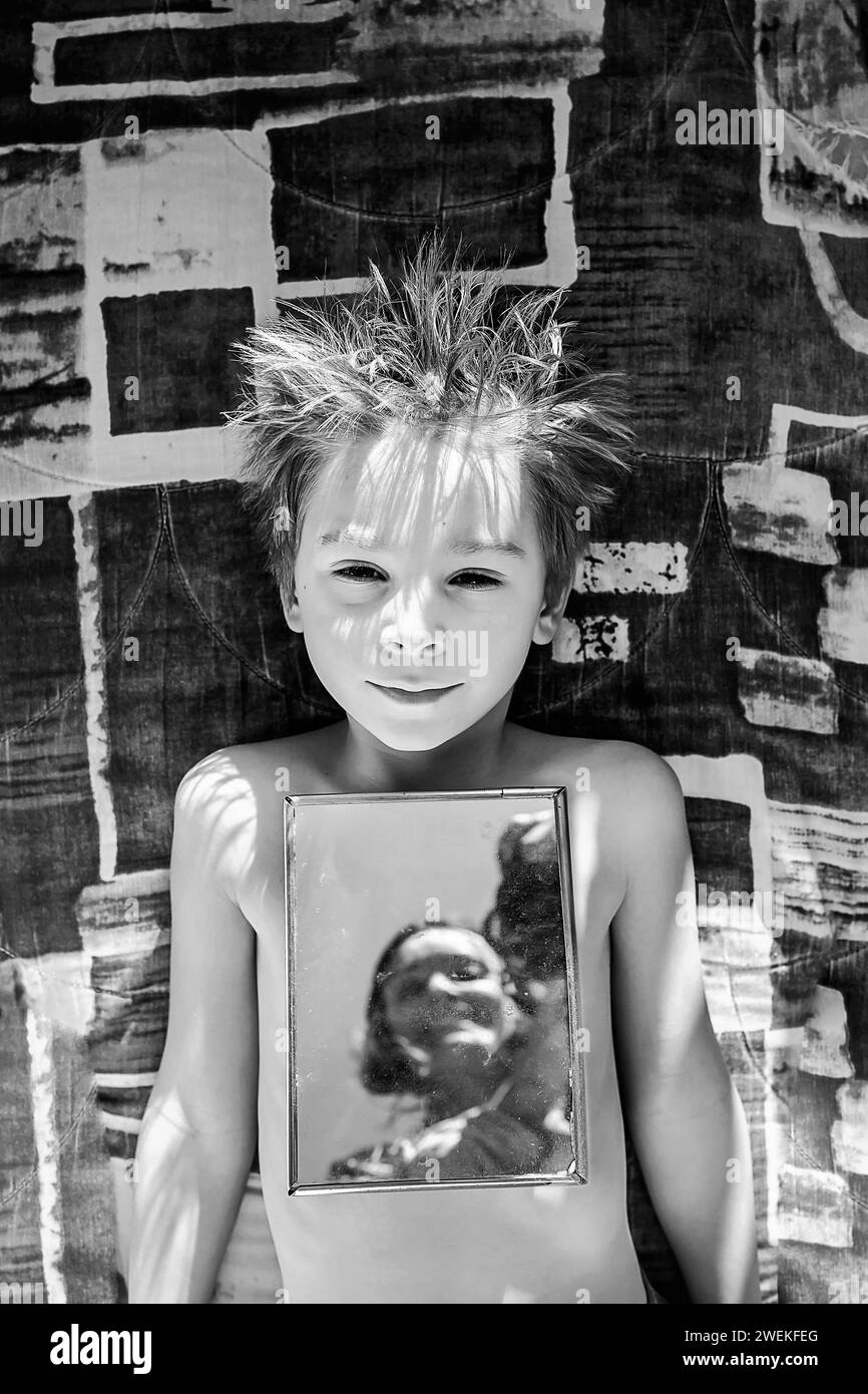 Cute child, boy, lying in bed with mirror, portrait in the mirror with