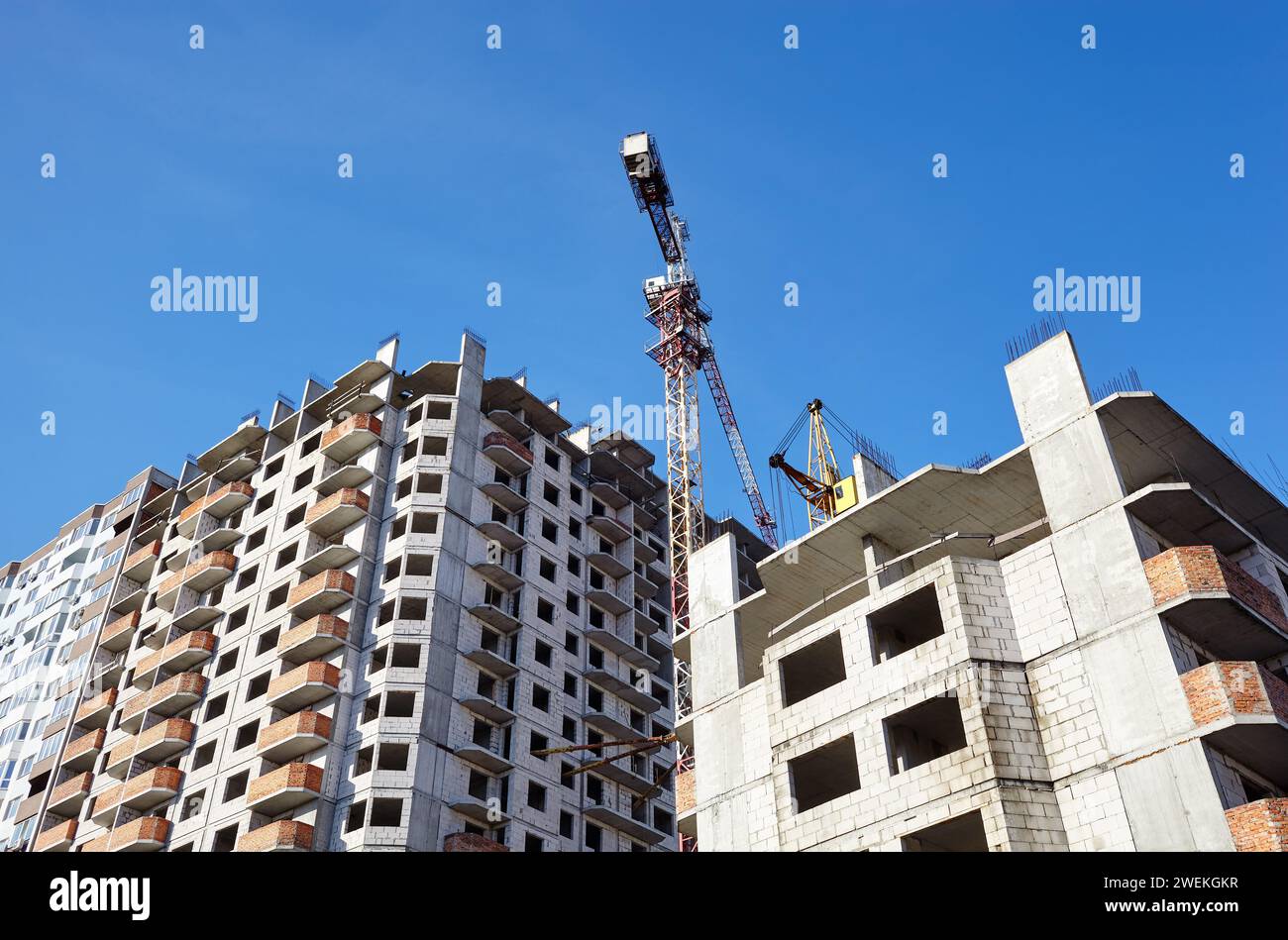 Tower cranes building a house. Concrete building under construction. Construction site Stock Photo