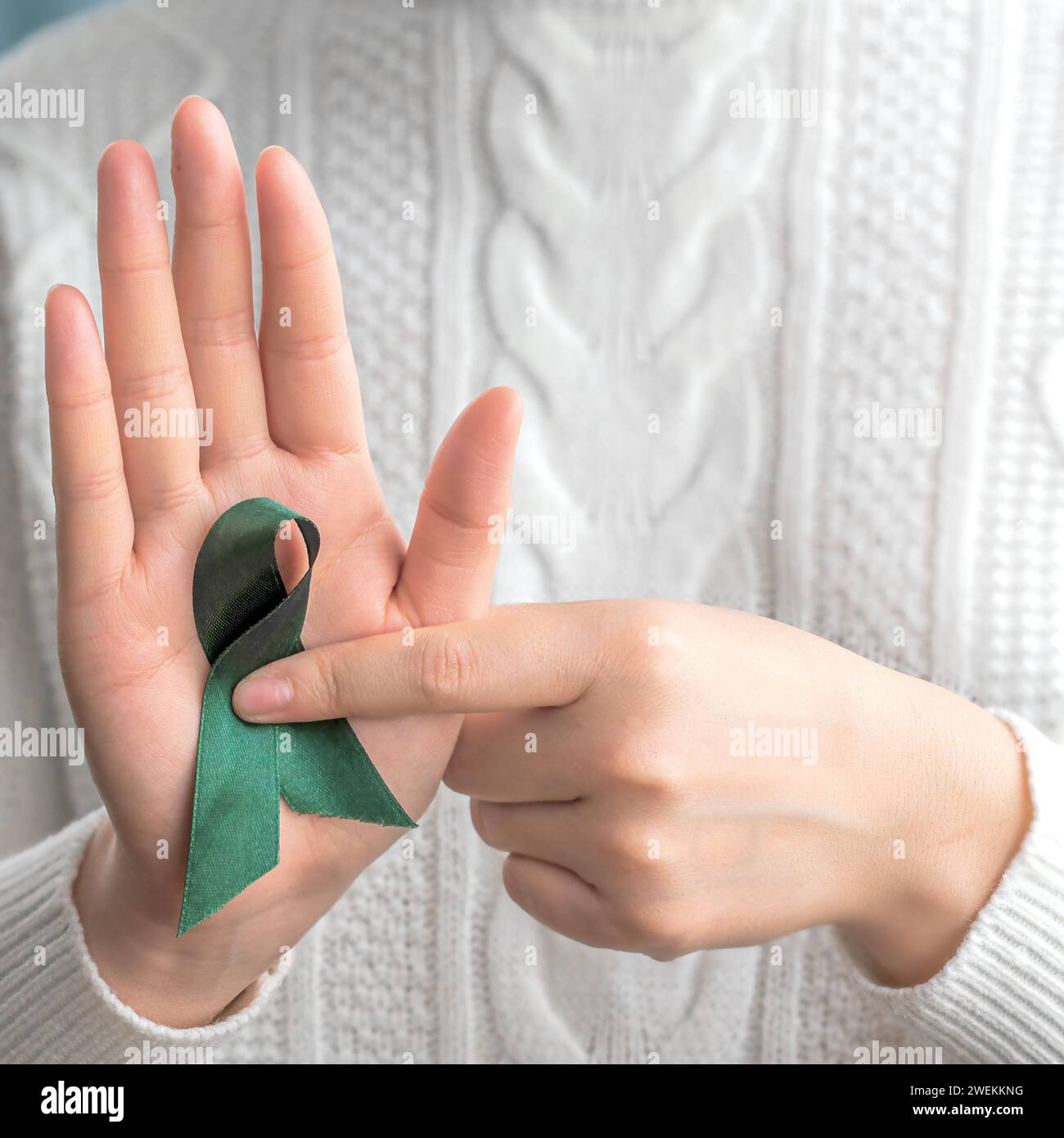 A woman with green ribbon. Hands holding green ribbon. Healthcare and world cancer day concept Stock Photo