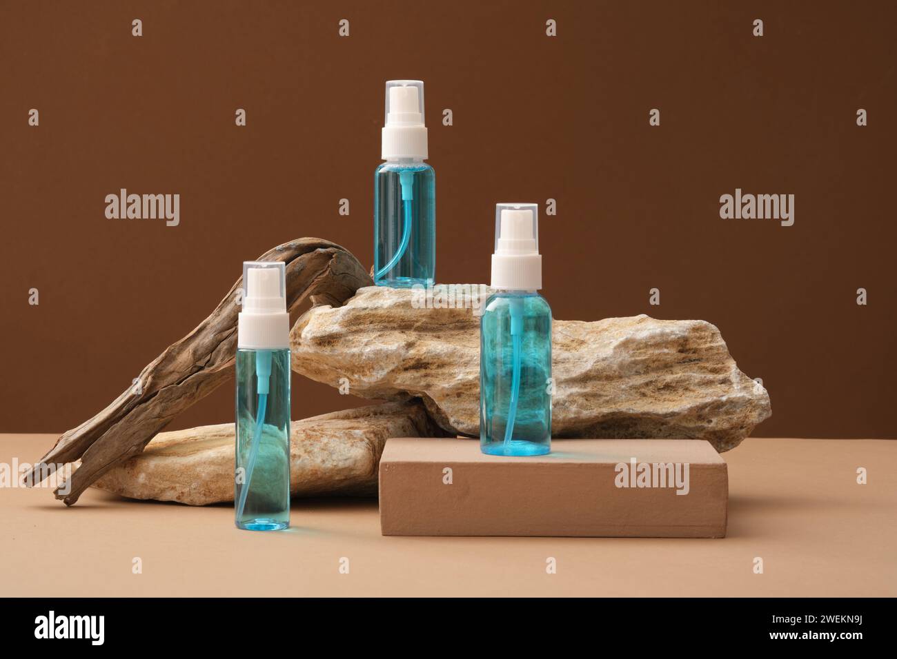 Front view of three blue spray bottles unlabeled placed on brown podium