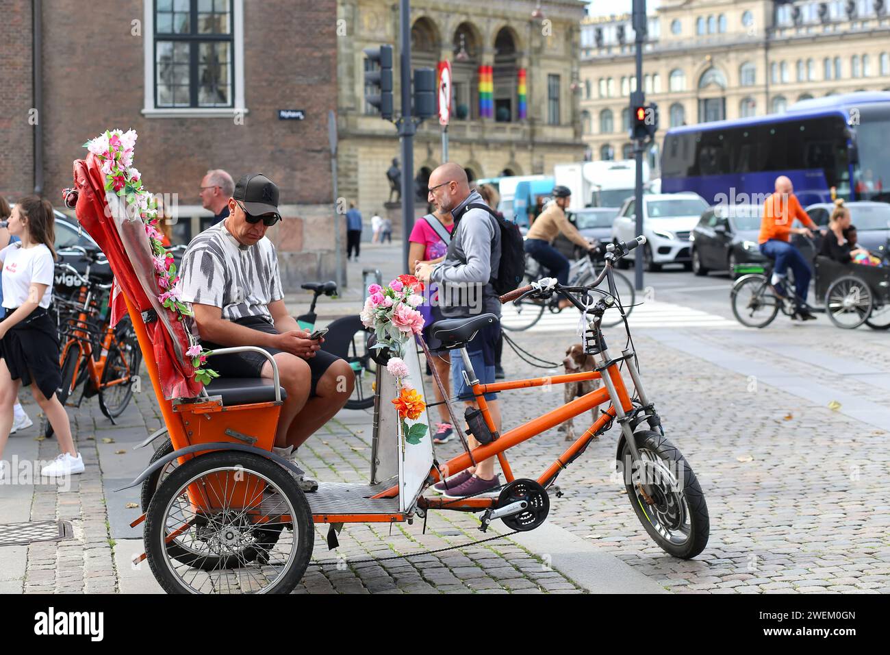 Copenhagen, Denmark - August 17, 2023: the Nyhavn Canal.: People riding bicycles in old city center. Man sitting on wheelbarrow cargo bike. Movement i Stock Photo