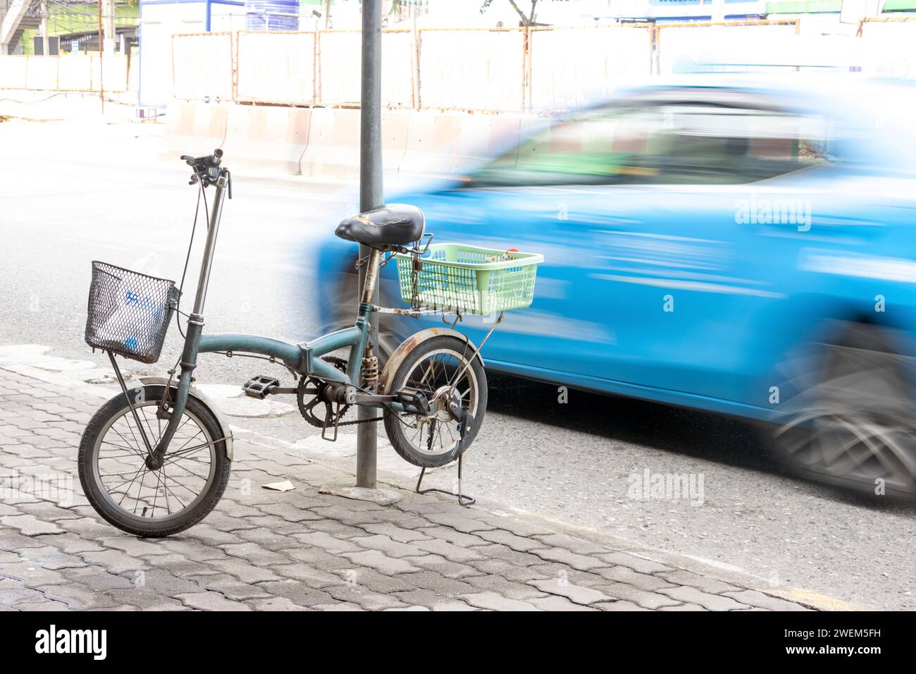The bicycle parked on a kickstand on the sidewalk next to a busy road, Bangkok, Thailand Stock Photo