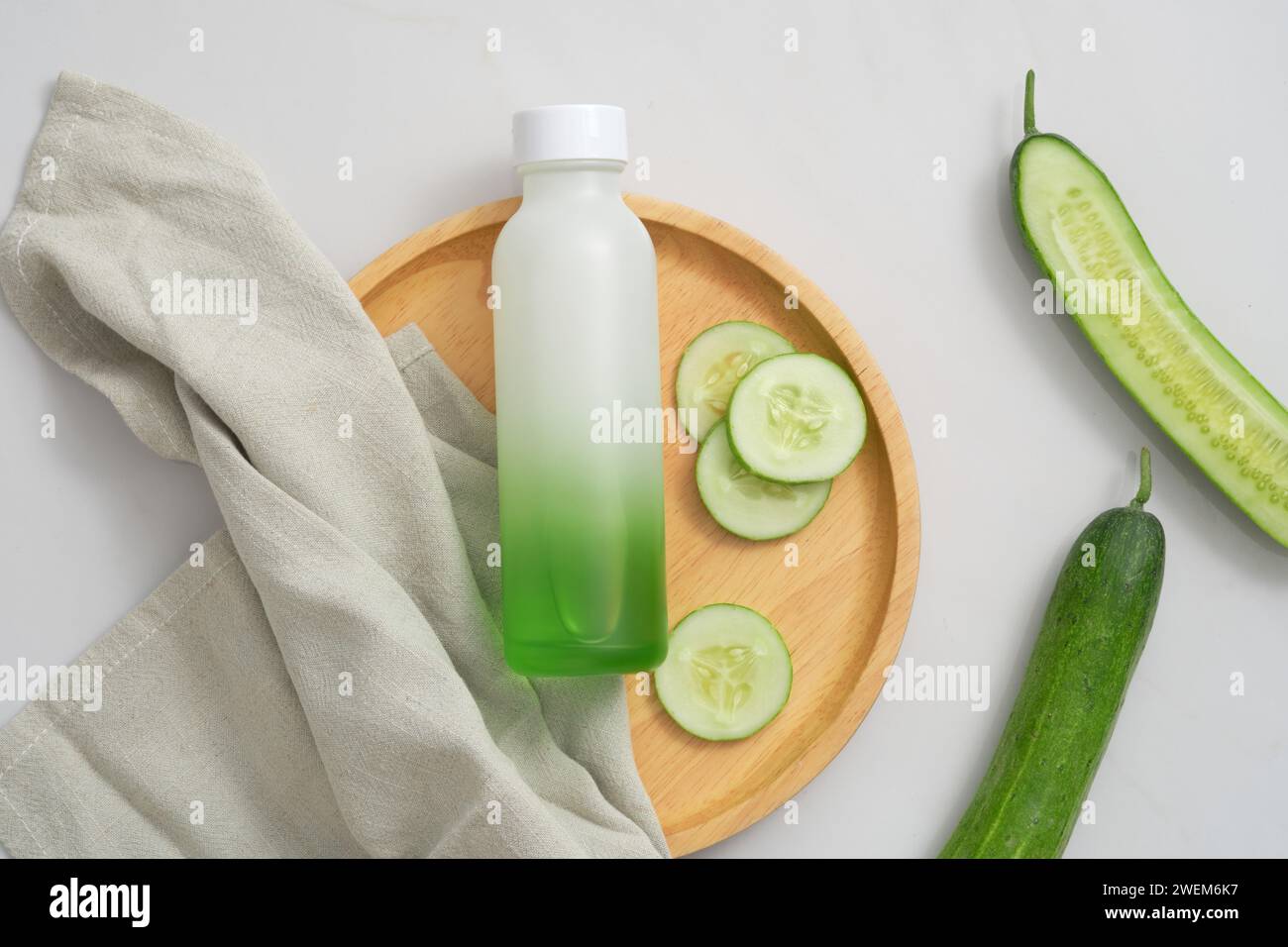 Top view of toner bottle unlabeled, cucumber slices and gray towel on ...