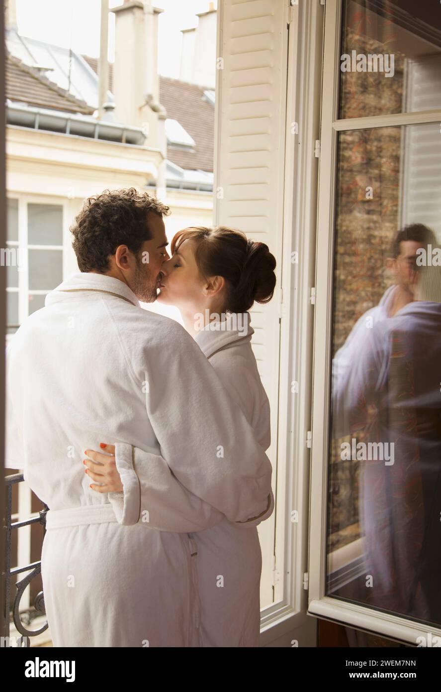 Couple kissing in front of an open window Stock Photo