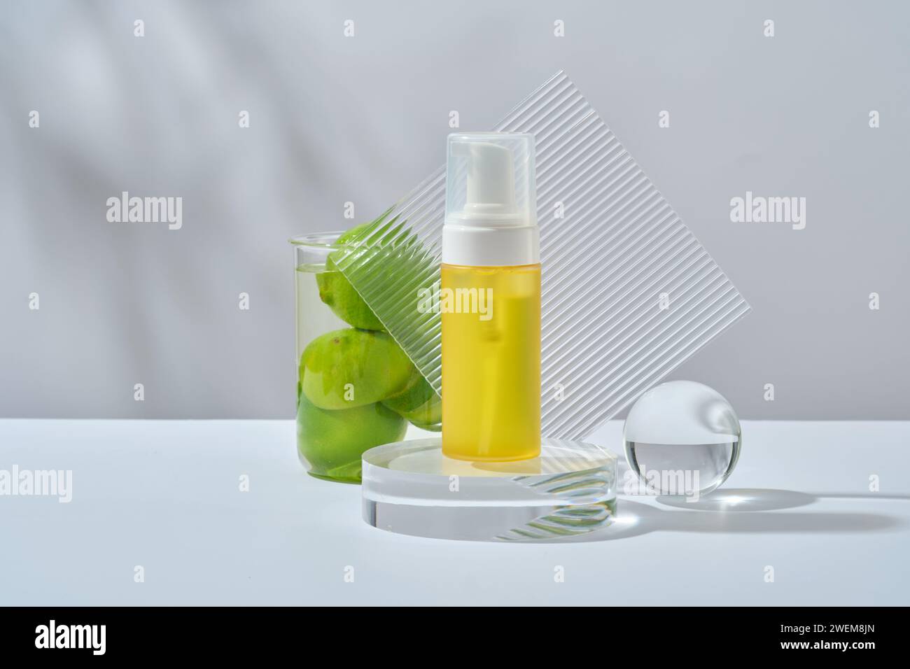 An unlabeled bottle on podium, lime, acrylic sheet and glass ball on