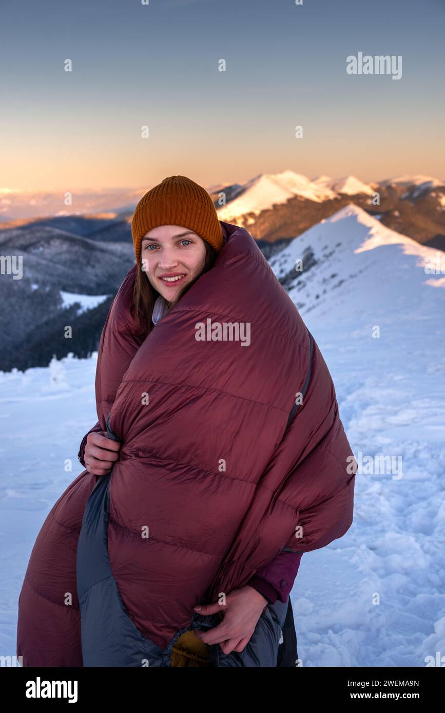 Portrait of Smiling Young Woman Wrapped in a Sleeping Bag Stock Photo