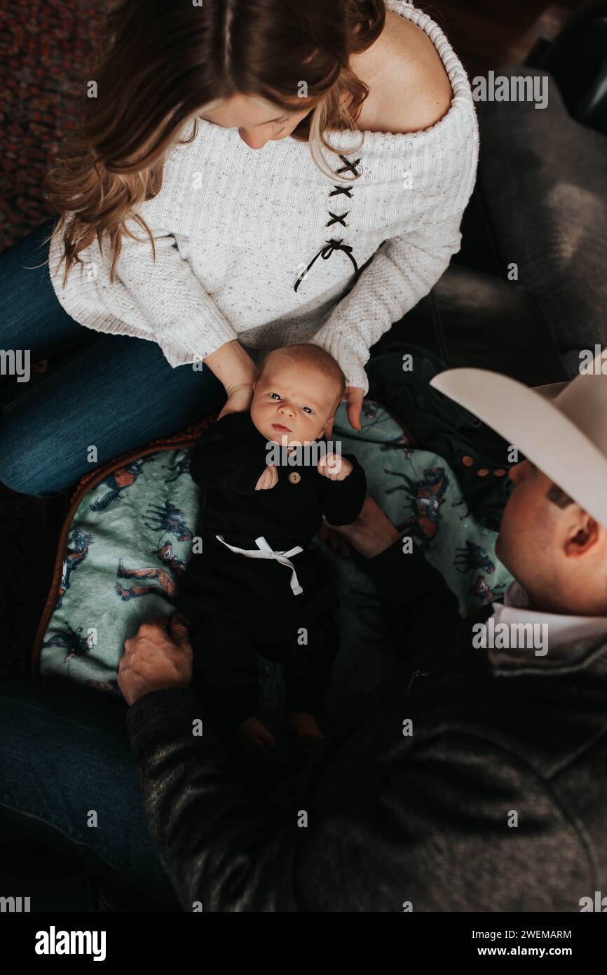 Mom and dad change baby boy's outfit on the couch Stock Photo