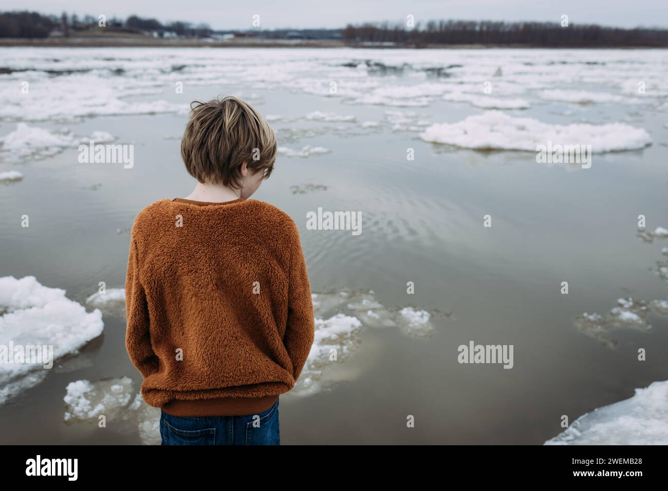 Child looking out at ice floating down Mississippi River Stock Photo