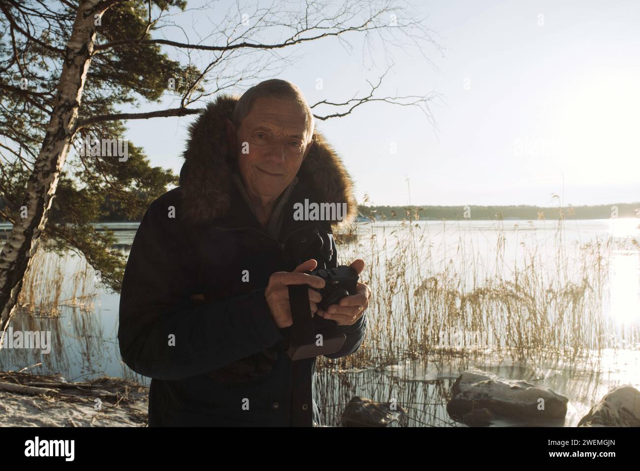 portrait of man taking pictures of a lake in the snow in Sweden Stock Photo