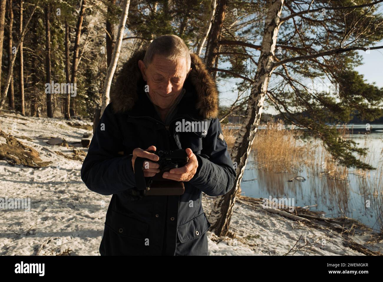 retired man looking at his camera by the lake in Sweden Stock Photo
