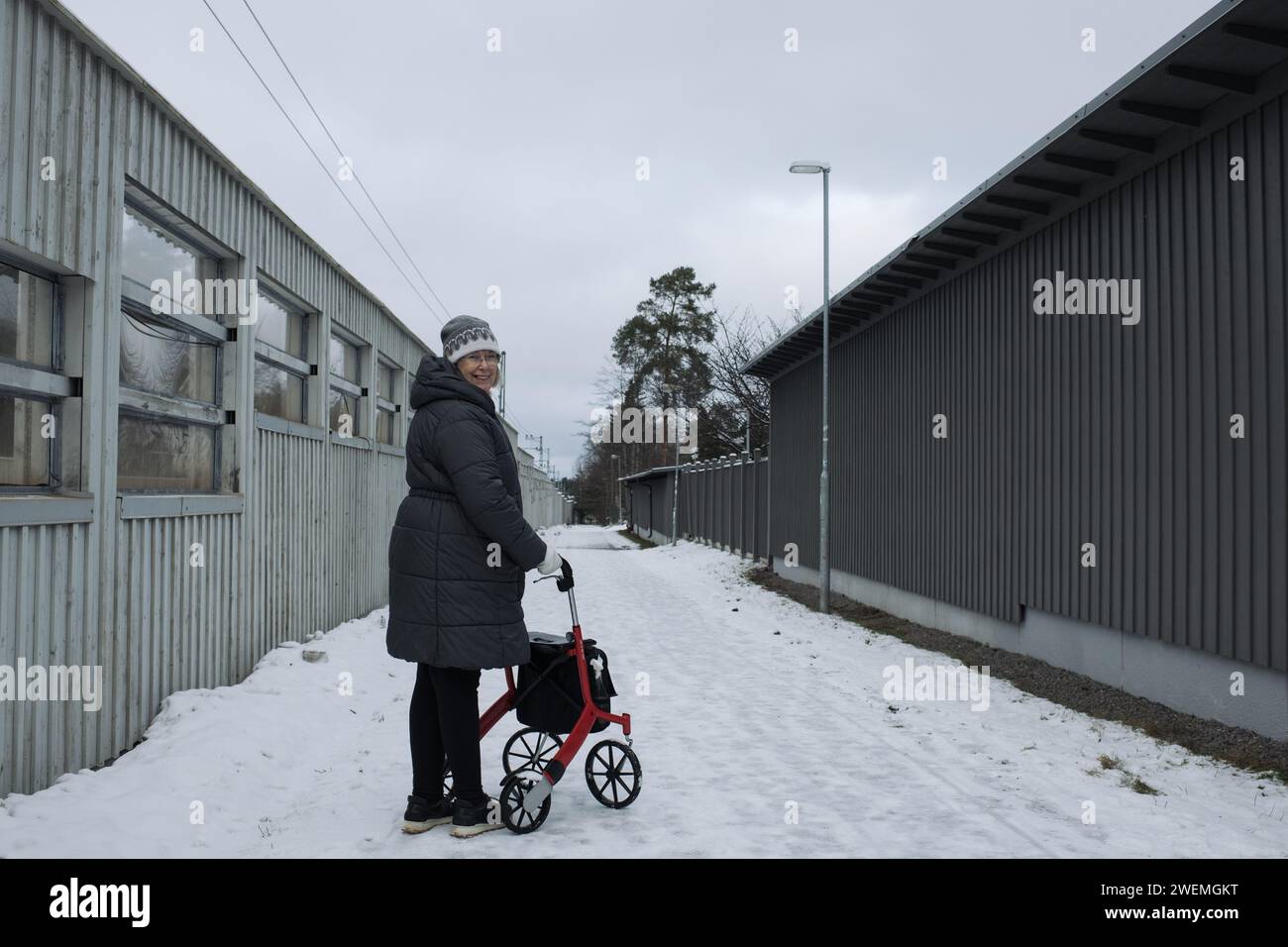 retired woman happily walking in the snow with her rollator Stock Photo