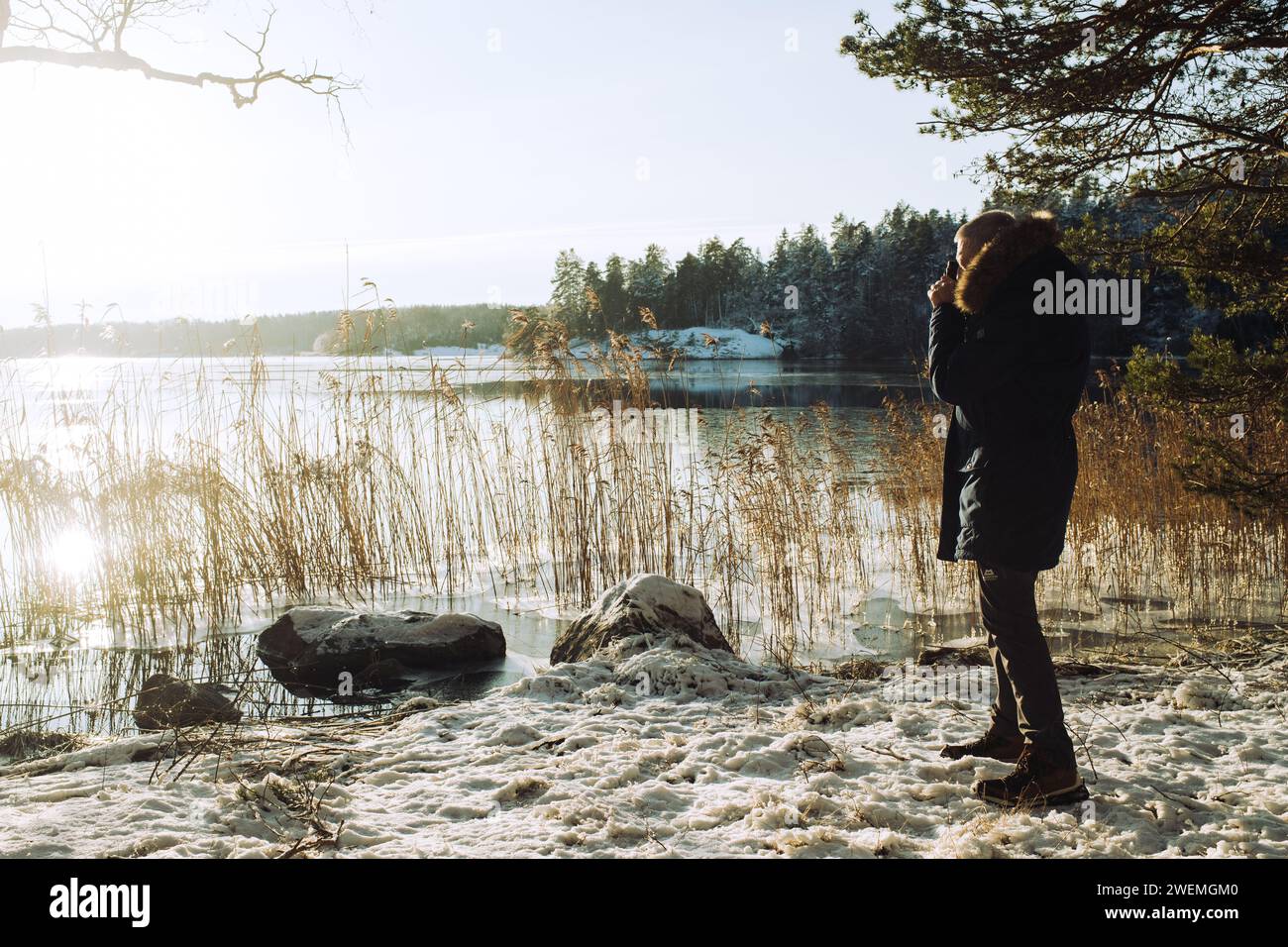 retired man taking pictures of a lake in Sweden in the snow Stock Photo