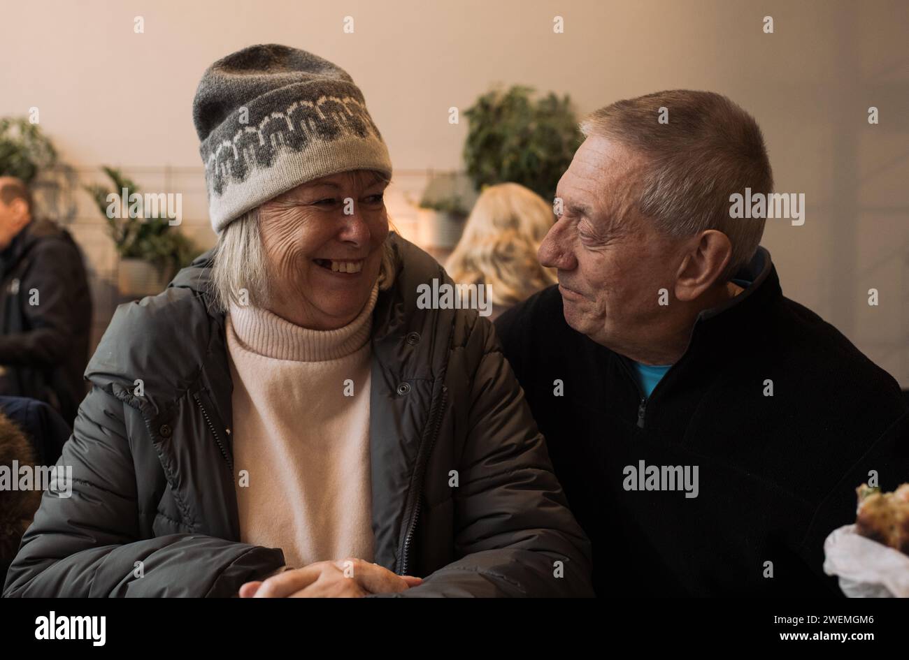 retired couple in their 70's sat laughing together in a cafe Stock Photo