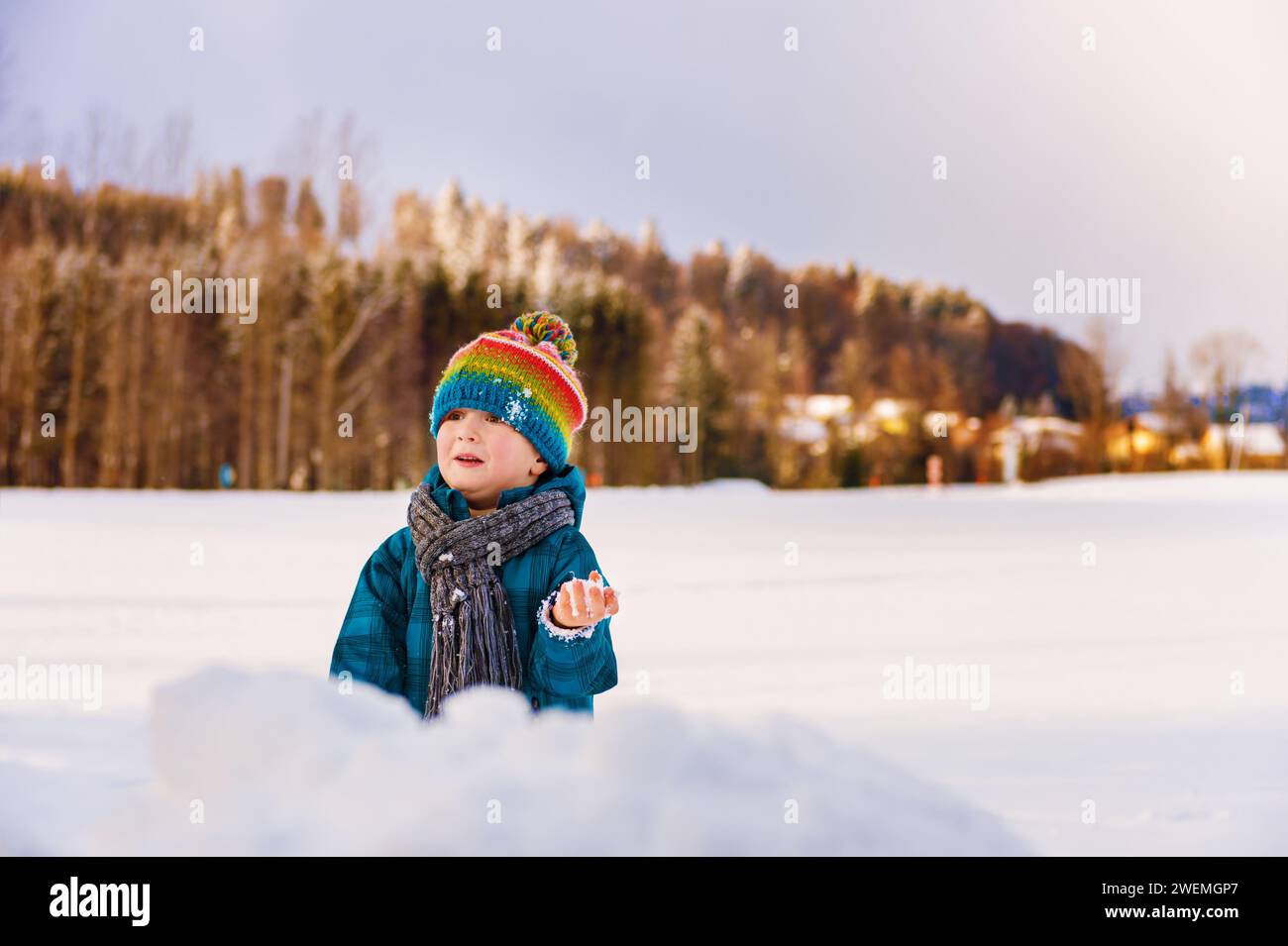 Cute little boy playing in snow field. Kid having fun outdoors, running on snow, wearing warm blue jacket, hat and scarf Stock Photo