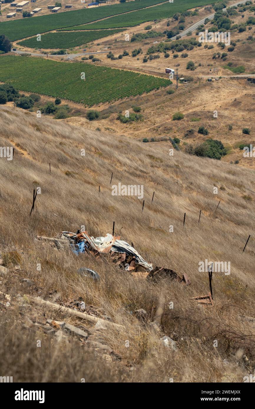 Hill side of dry grass and metal scrap on mine field Stock Photo