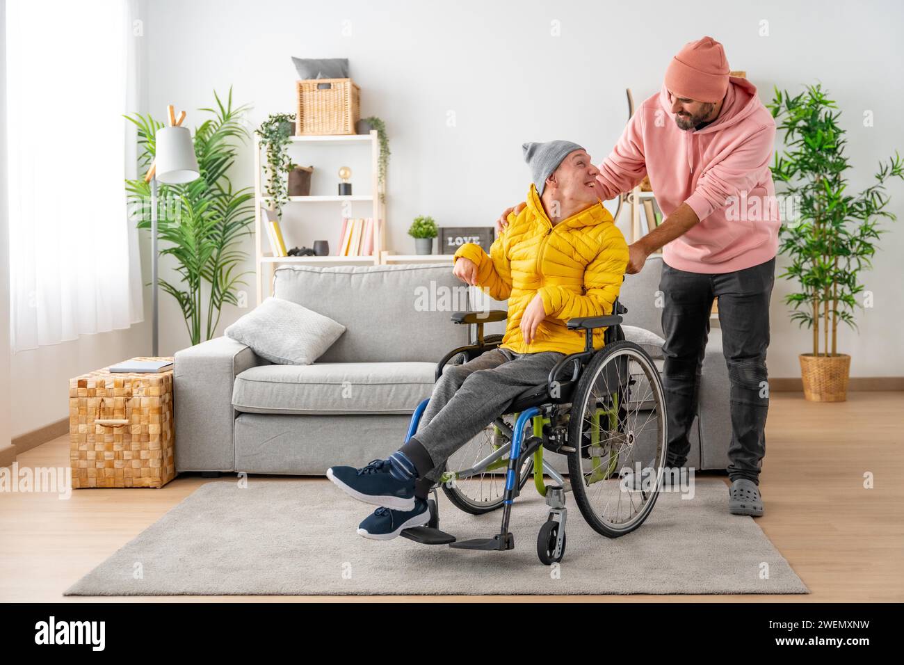 Happy disabled man with a and friend holding the wheelchair at home Stock Photo