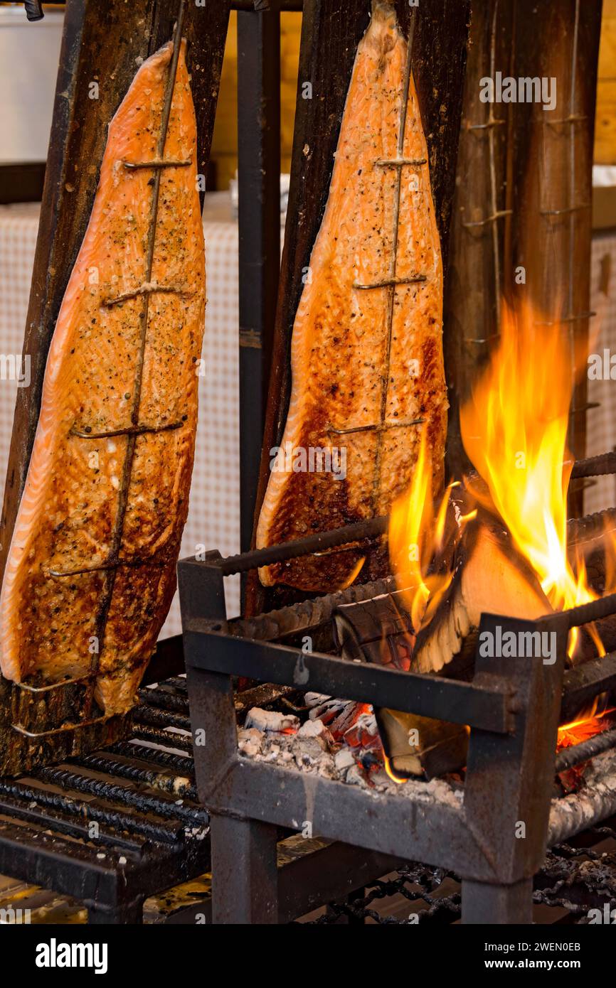 Flame-grilled salmon in a fire bowl, fillets of salmon grilled over an open flame, fish cooked, speciality from Finland, Leumulohi, snack bar, market Stock Photo
