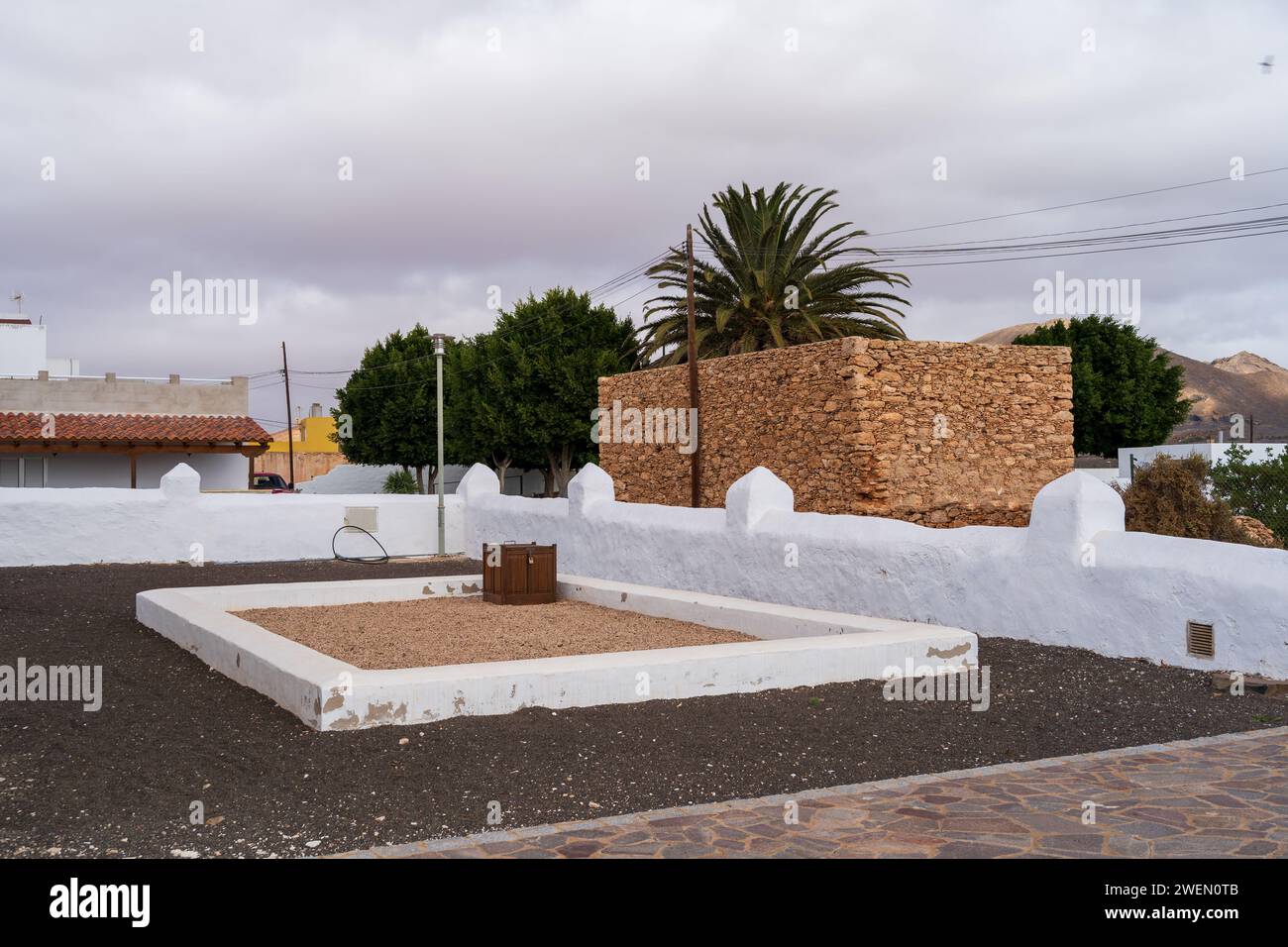 A serene view of Ermita de San Marcos grounds with a stone structure and palm tree. Stock Photo