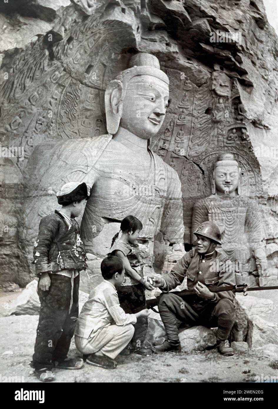 S9NO-JAPANESE WAR 1937-1945.  Japanese propaganda photo purporting to show a chivalrous side of the Japanese occupation of Manchuria. Here a Japanese soldier plays with local children outside the Yungang caves inShanxi. Stock Photo