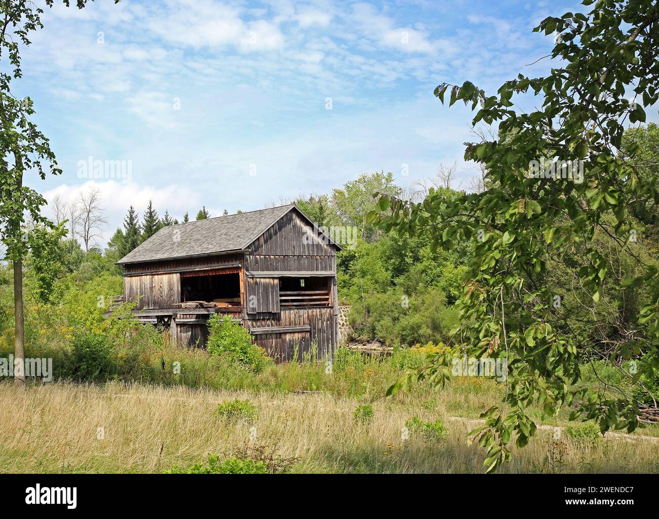 Old Sawmill Wooden Building in country, partly clouded sky with trees. Stock Photo