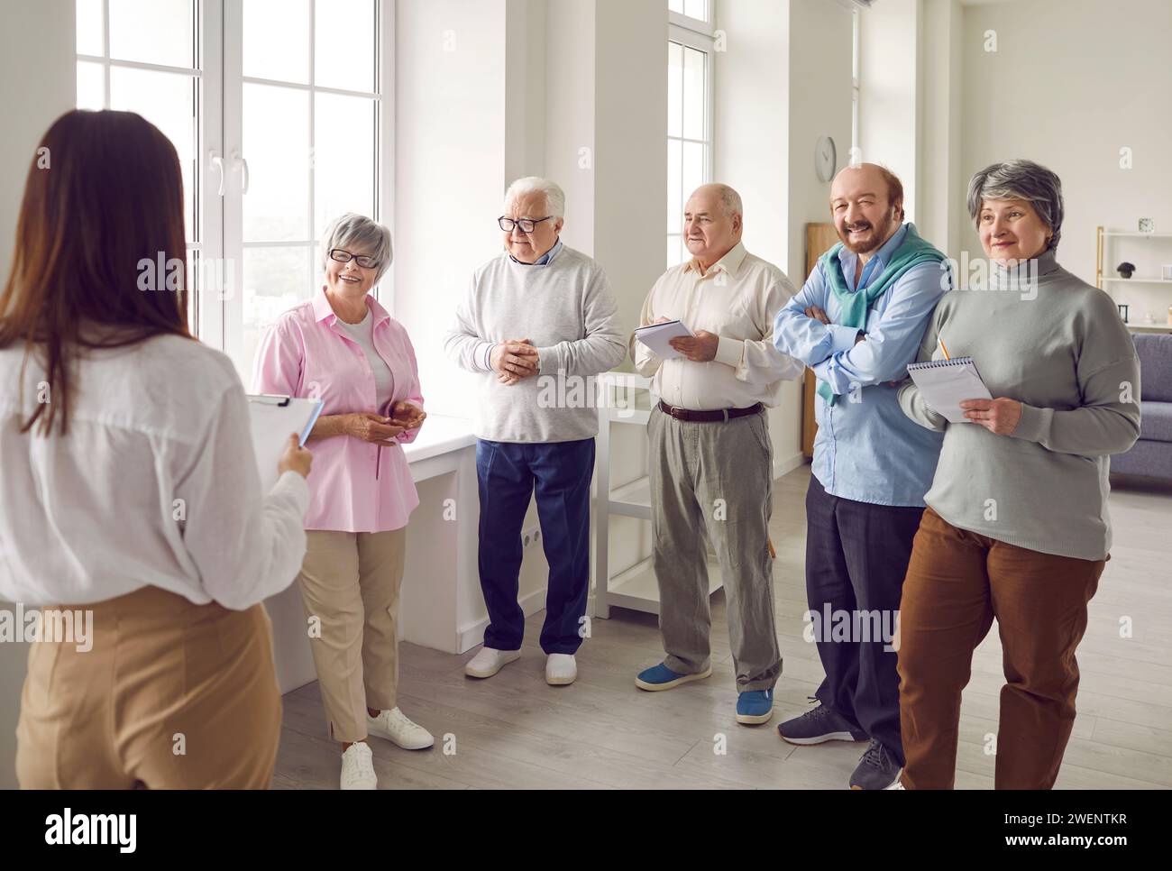 Group of happy senior people taking notes while listening to coach or psychologist Stock Photo