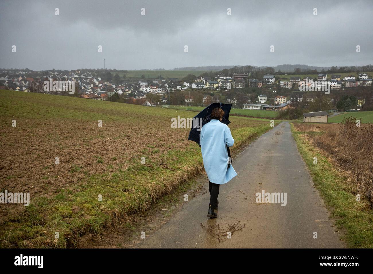 Spaziergang im Sturm: Frau und Hund trotzen Regen und Wind 26.01.2024, Selters: Symbolfoto, Illustrationsbild, Symbolbild, Illustrationsfoto Spaziergang im Sturm: Frau und Hund trotzen Regen und Wind Eine Frau kämpft mit ihrem Regenschirm, während sie gemeinsam mit ihrem treuen Hund auf einem Feldweg spaziert. Trotz des stürmischen Wetters, mit starkem Regen und Wind, bleibt das Duo unerschütterlich auf ihrem Weg durch die Natur Selters Hessen Germany *** Walking in a storm Woman and dog defy rain and wind 26 01 2024, Selters Symbol photo, Illustration image, Symbolbild, Illustration photo Wal Stock Photo