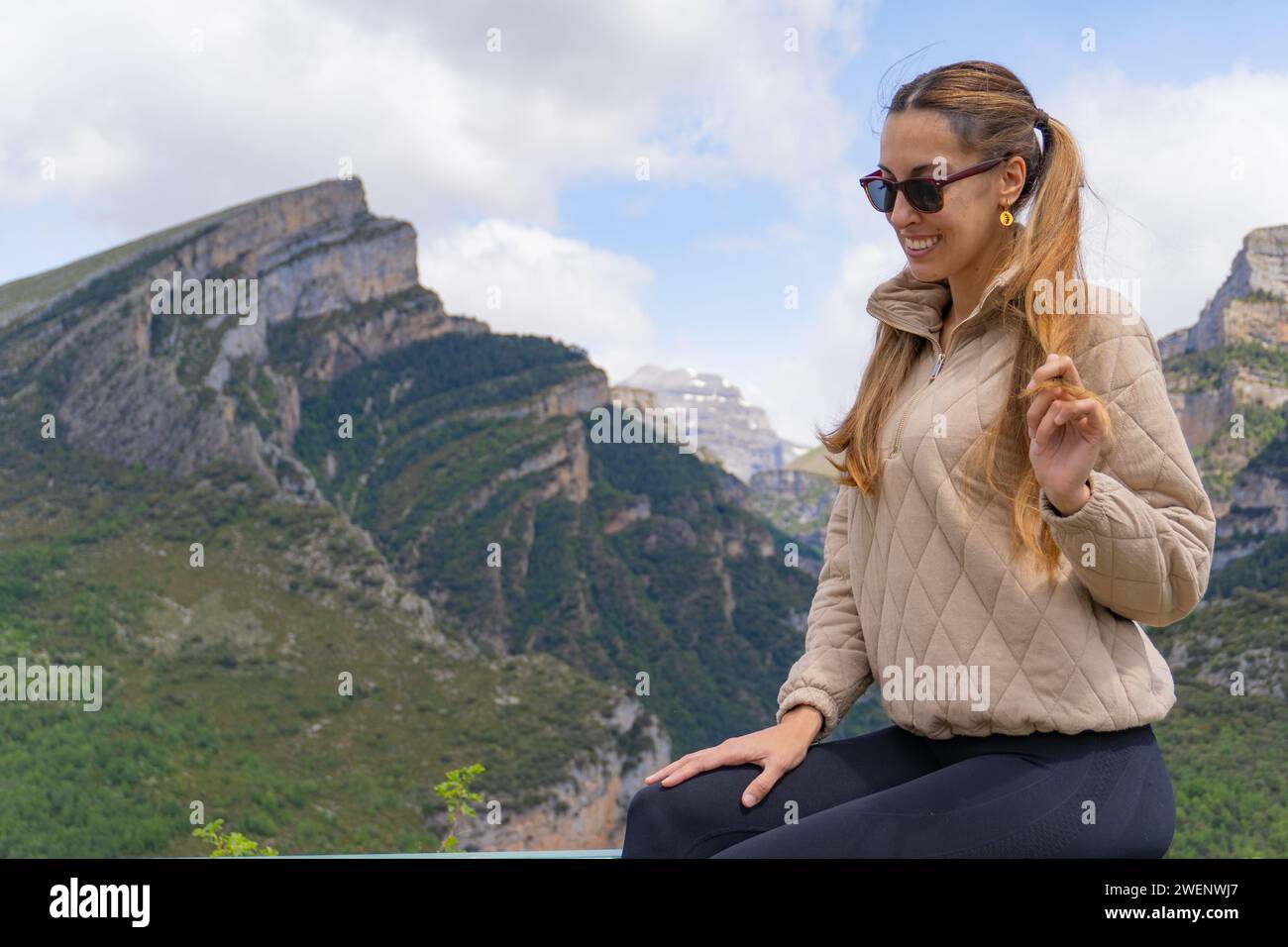portrait of a woman sitting on a viewpoint, with sunglasses and ...