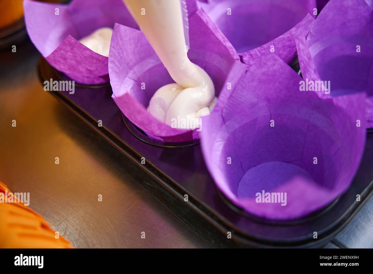 Disposable paper baking molds being filled with pastry dough Stock