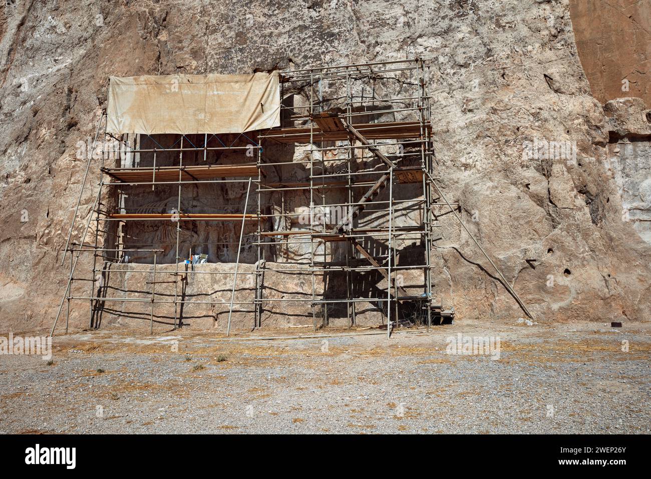 Rock relief “Victory of king Shapur I over Roman emperors Valerian and Philip the Arab” covered by scaffolding for restoration. Naqsh-e Rostam, Iran. Stock Photo