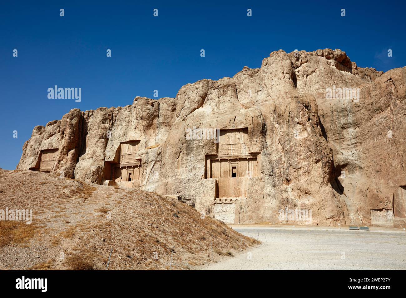 View of the Naqsh-e Rostam Necropolis, low rocky hill (aka Hossein mountain) with rock-cut tombs of kings of Achaemenian dynasty near Persepolis, Iran Stock Photo