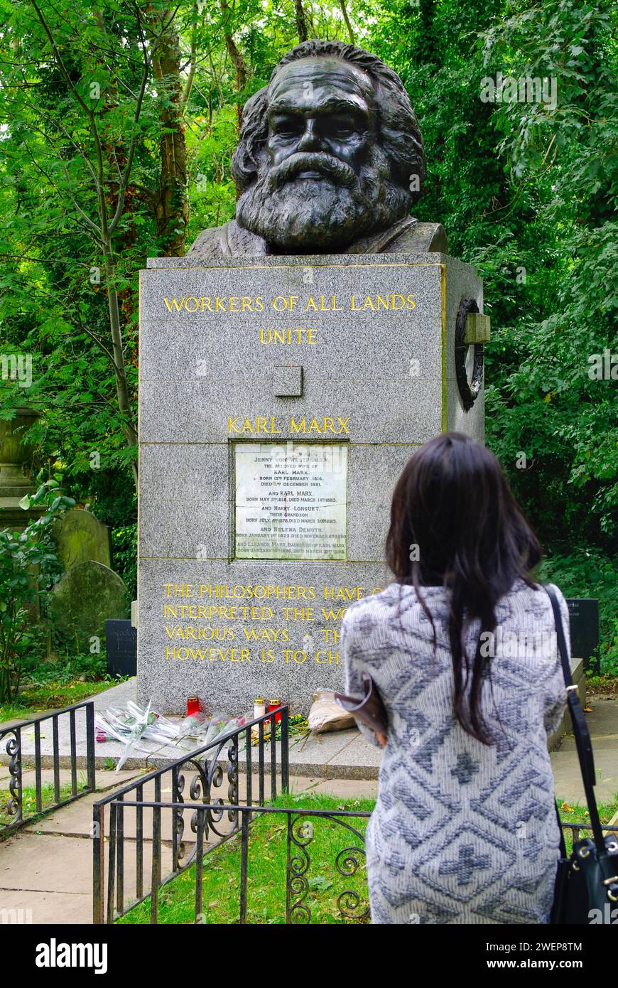 London: Am Grab von Karl Marx. - Eine junge Frau steht auf dem Highgate-Friedhof in London mit erhobener Faust neben der gepflegten Grabstätte von Kar Stock Photo