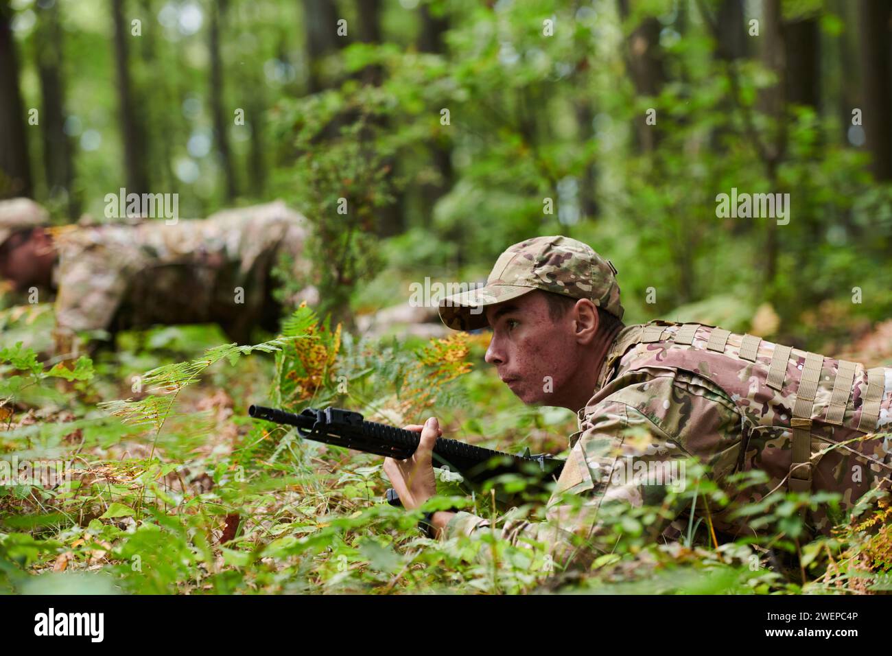 Elite soldiers stealthily maneuver through the dense forest, camouflaged in specialized gear, as they embark on a covert and strategic military Stock Photo