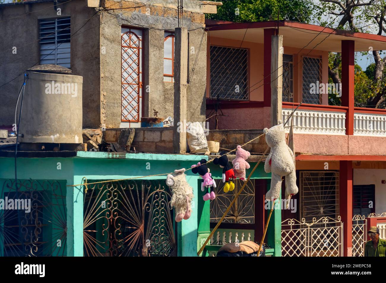 Stuffed toys drying on a clothes line, Facade of houses, Cuba Stock Photo
