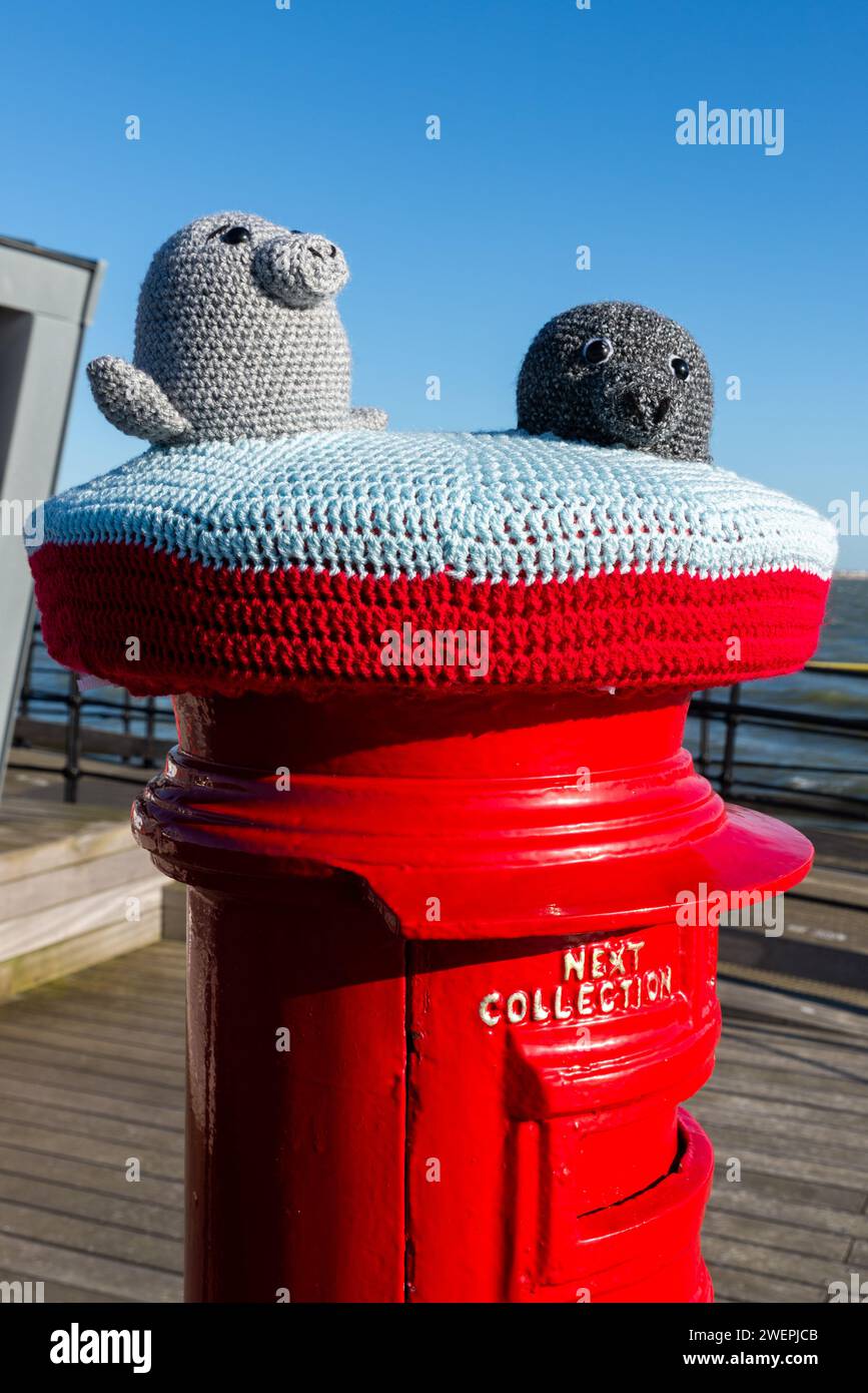 Yarn bombed post box on the end of Southend Pier, with grey seals knitted characters. Grey seals are often seen around the pier in the Thames Estuary Stock Photo