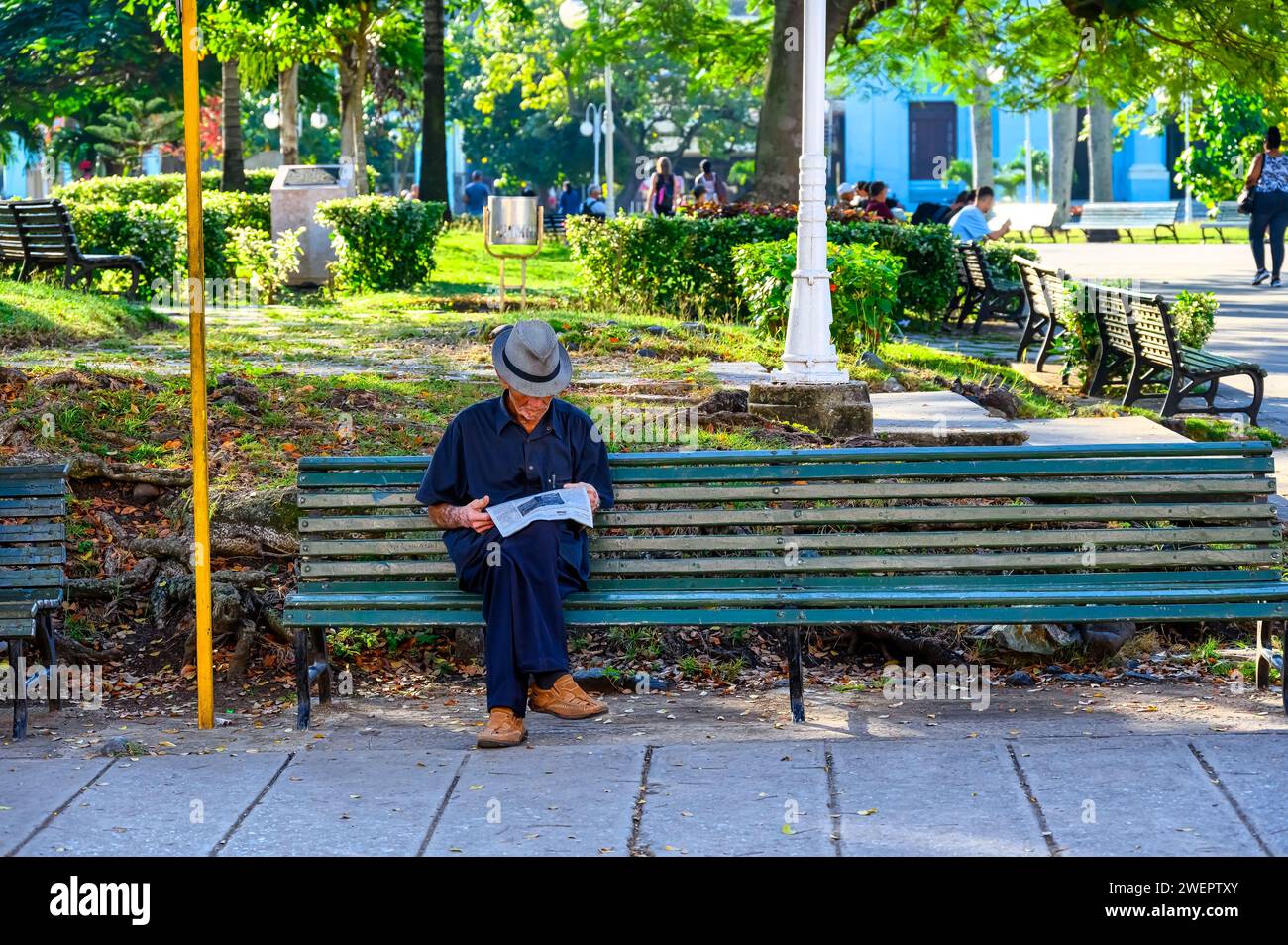 Senior man reading newspaper in park bench, Santa Clara, Cuba Stock Photo
