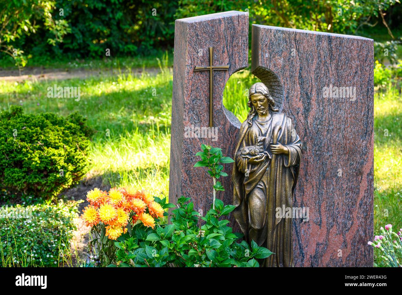 Decorated grave with a gravestone with cross and 'The Good Shepherd' figure Stock Photo