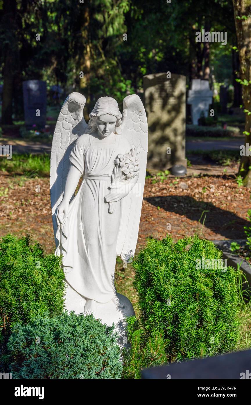White angel statue at the grave in the cemetery Stock Photo